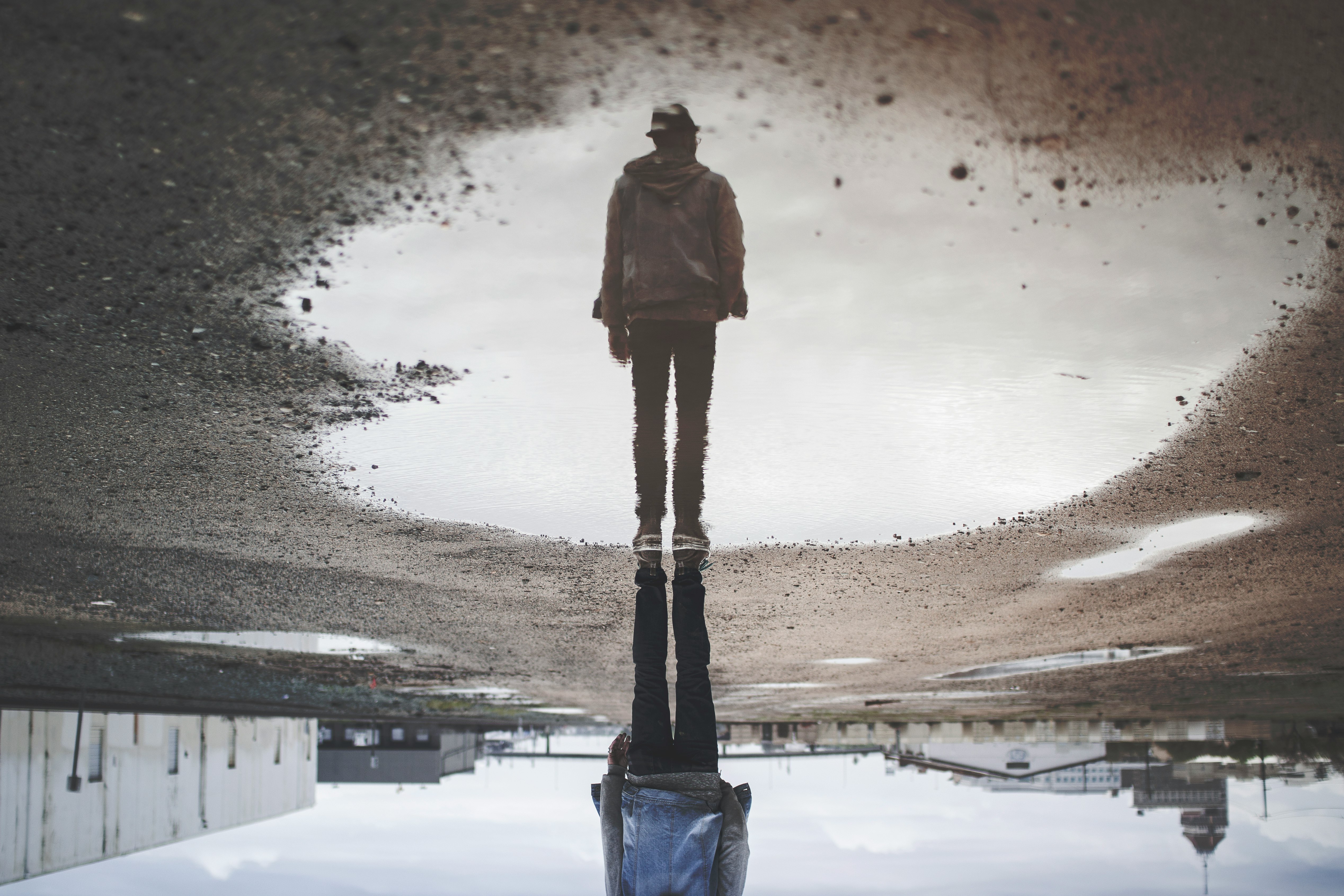 man's reflection on body of water photography